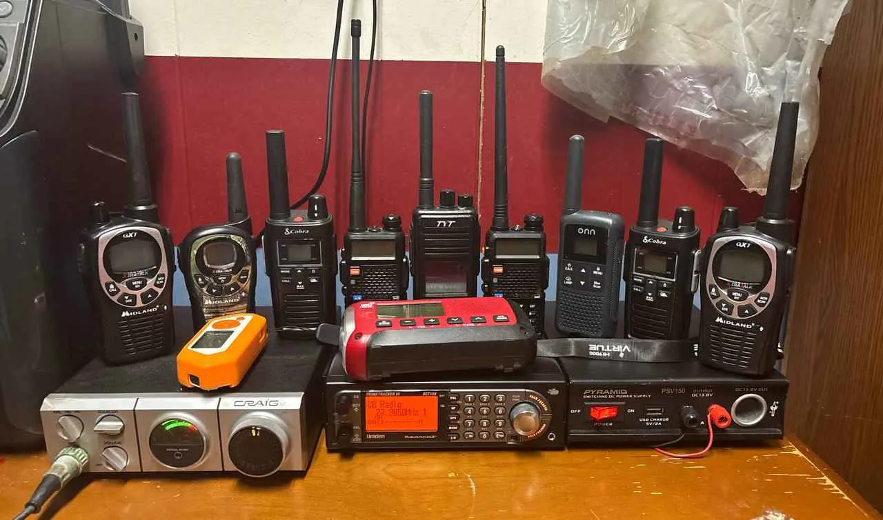 Sammy's collection of handheld radios, a scanner, CB equipment, and a power supply arranged on a workbench